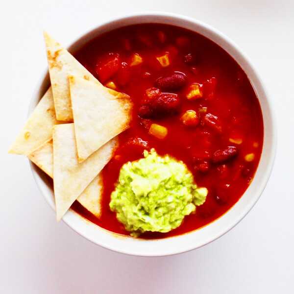 Spicy Mexican soup with baked tortilla chips and mashed avocado