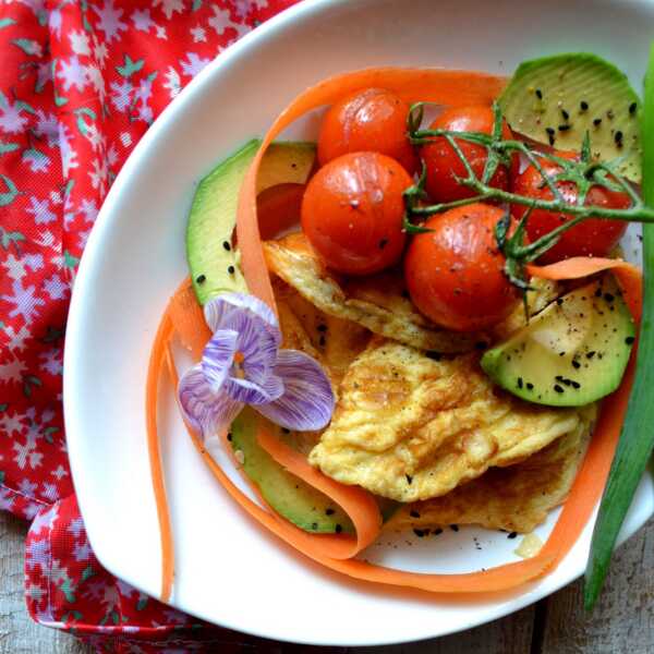 Omlet z pomidorkami, marchwią, awokado oraz czarnuszką. 